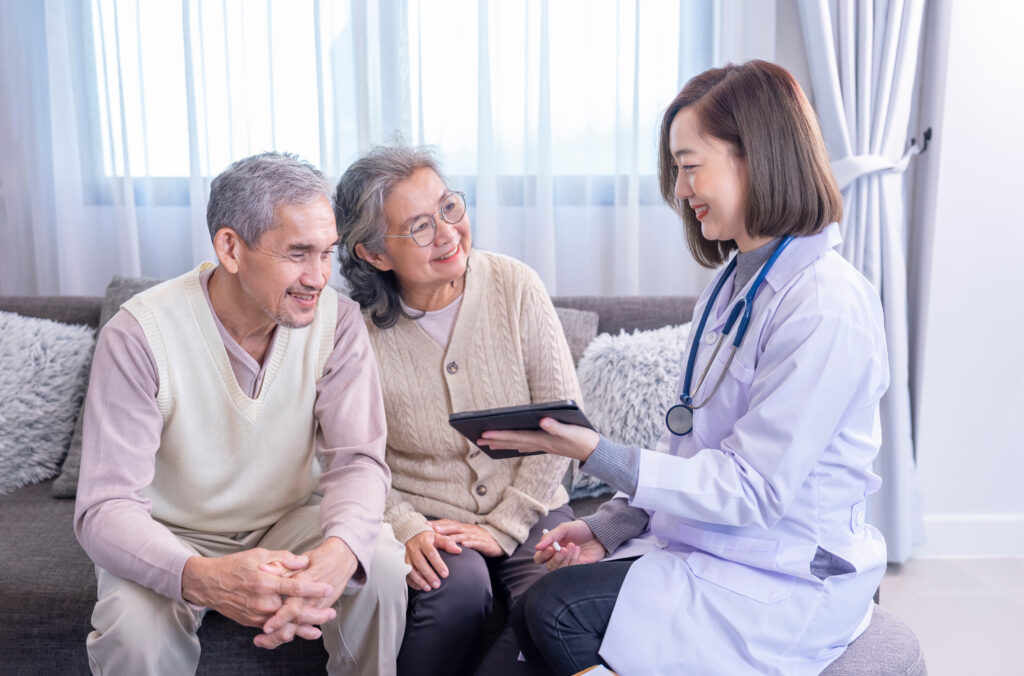 young female professional doctor giving consultation asian senior couple with using tablet computer in the room